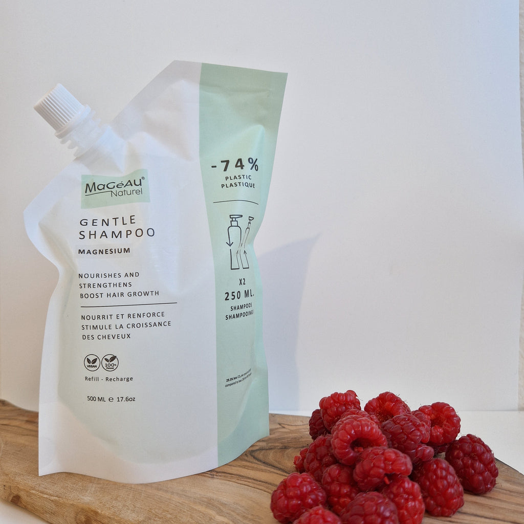 Mageau naturel magnesium shampoo bottle with green label on a white background, next to a wooden board with raspberries.