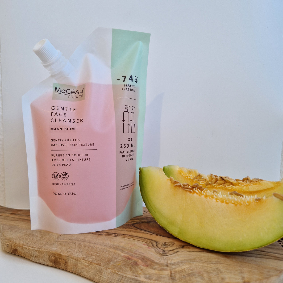 Pink bottle of Mageau naturel magnesium Gentle Face Cleanser with a slice of cantaloupe on a wooden cutting board.