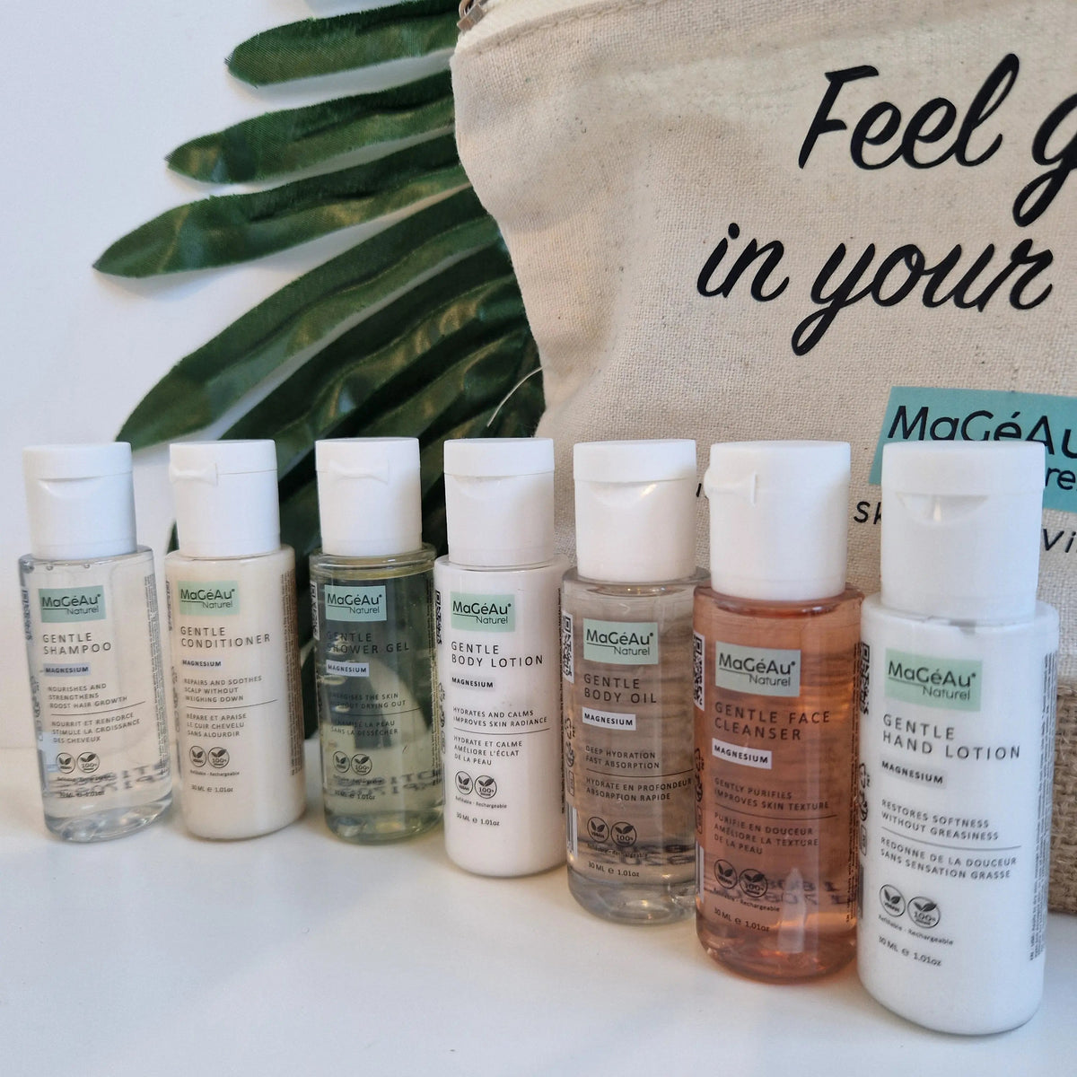 Row of MaGéAu Naturel skincare bottles with a beige bag and green leaves in the background