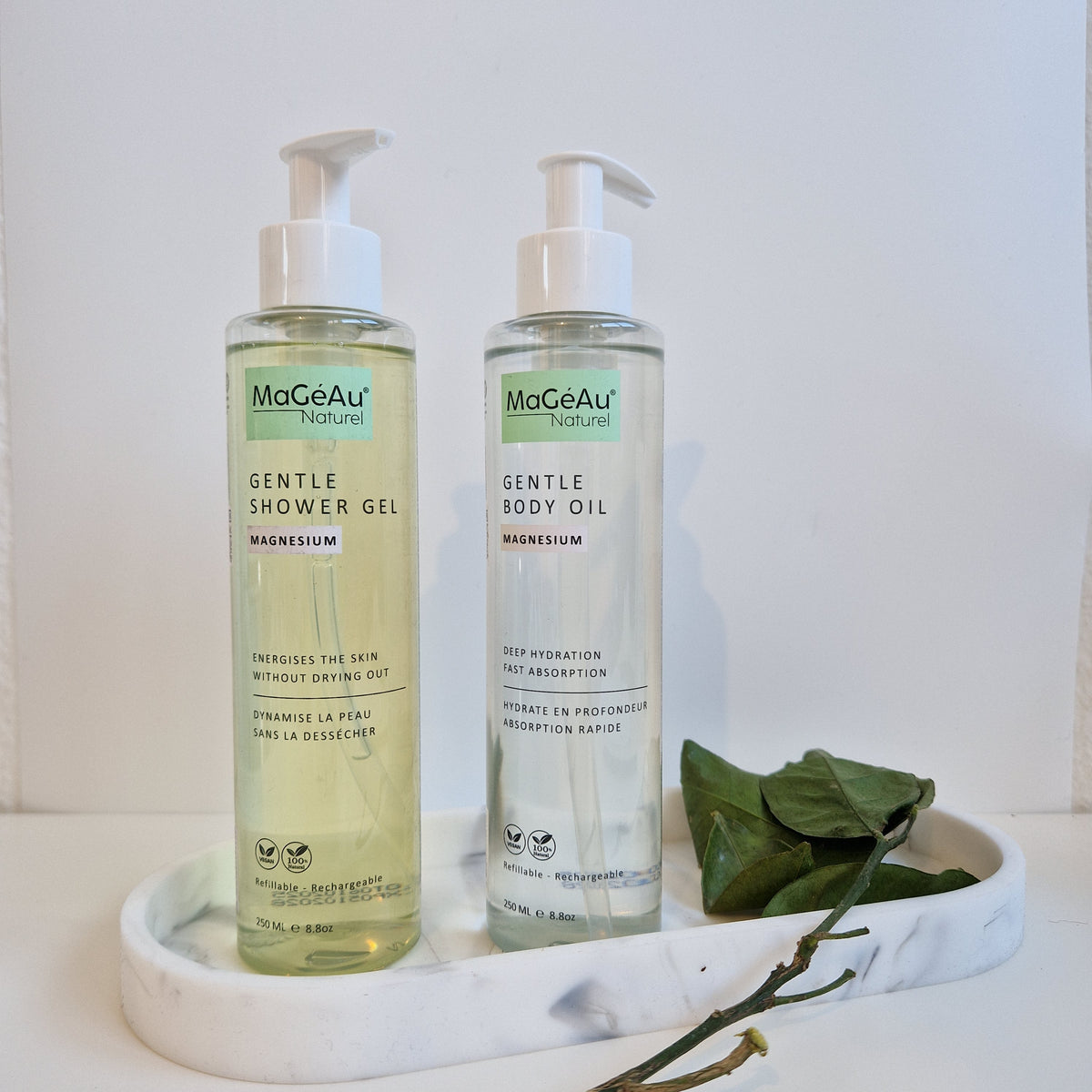 Two bottles of Mageau naturel magnesium  Gentle products on a white surface with green leaves.