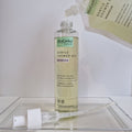 Tube of MaGéAu Naturel Gentle Shower Gel on a white surface with a clear container in the background.