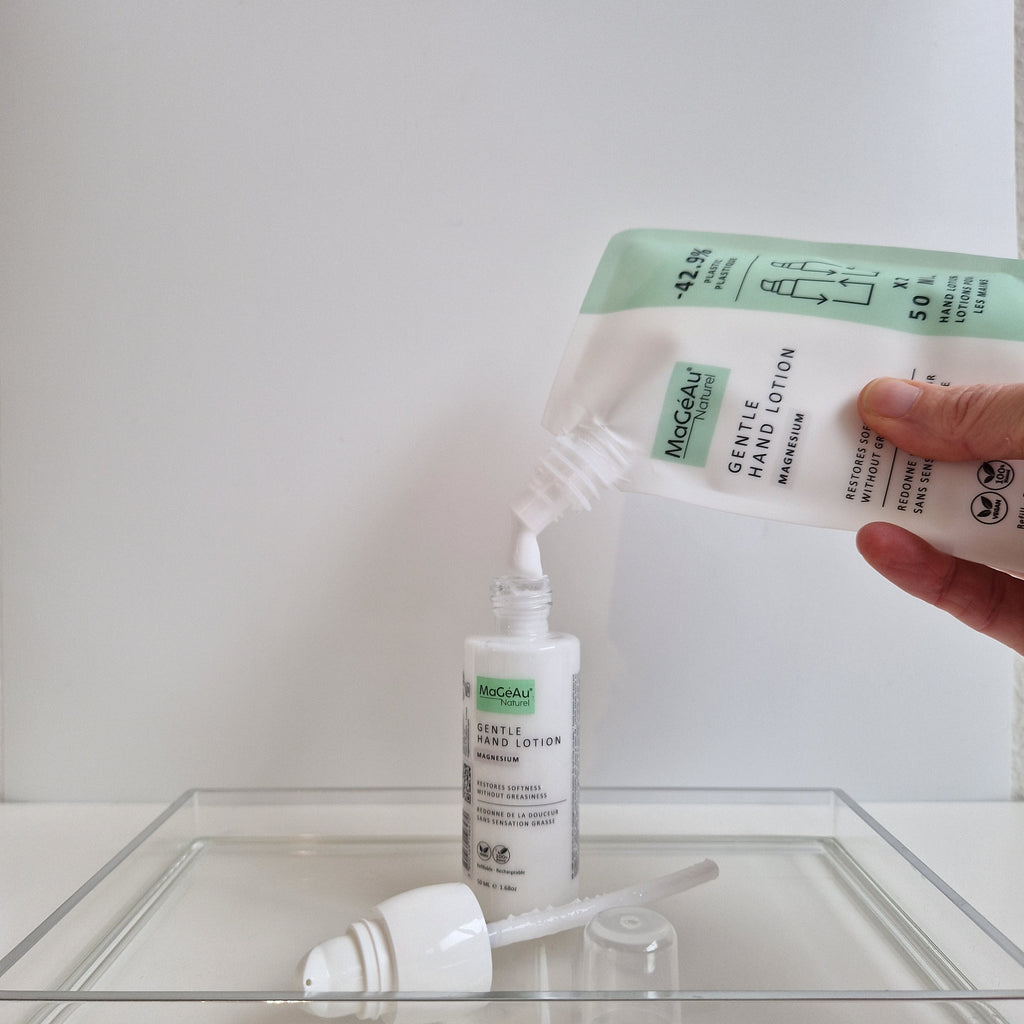 MaGéAu Naturel lotion from a bottle into a small container on a white surface.