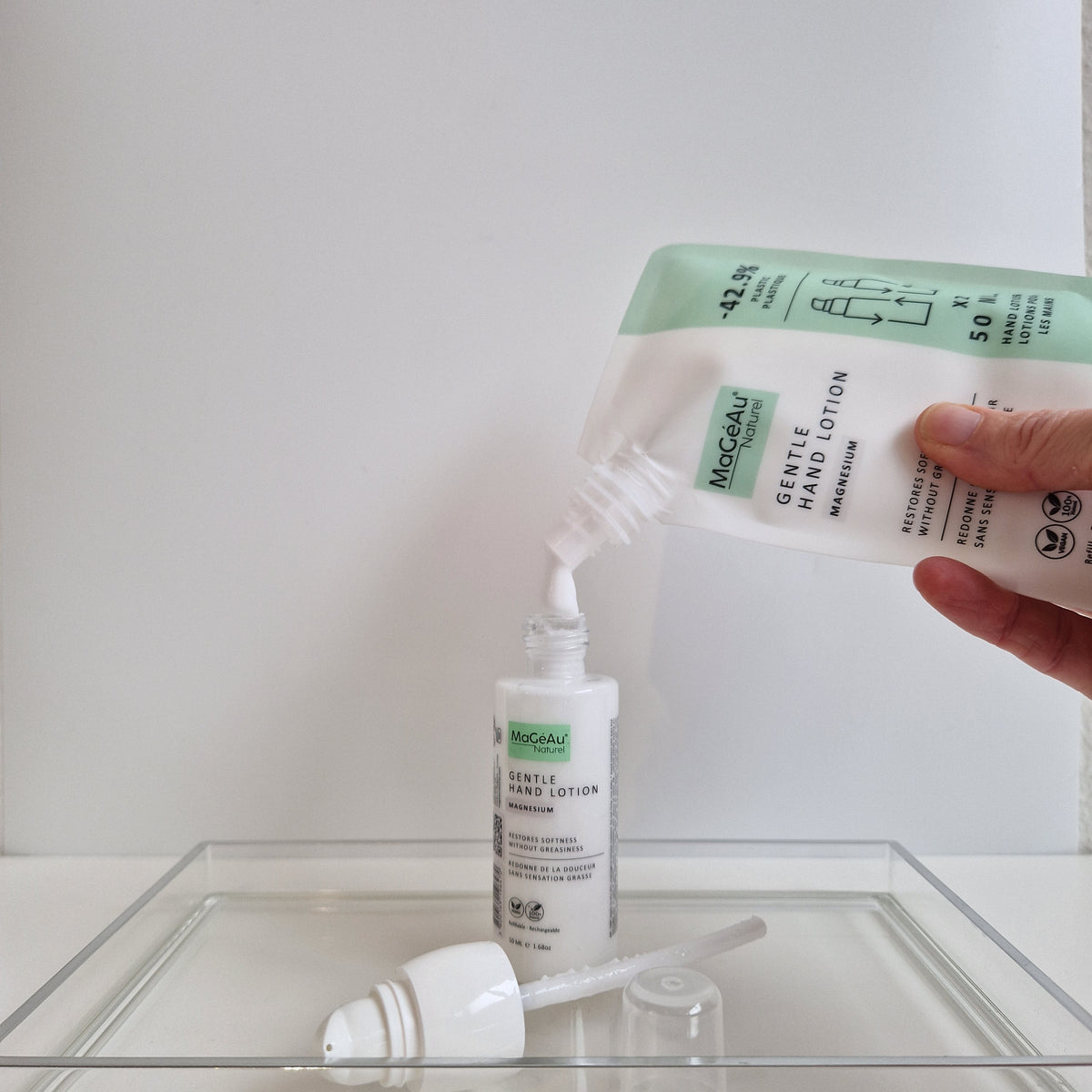 MaGéAu Naturel lotion from a bottle into a small container on a white surface.