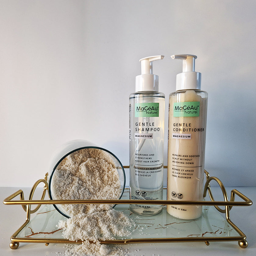 Two bottles of MaGéAu Naturel Magnesium Gentle Shampoo and Gentle Conditioner on a glass tray with a white background